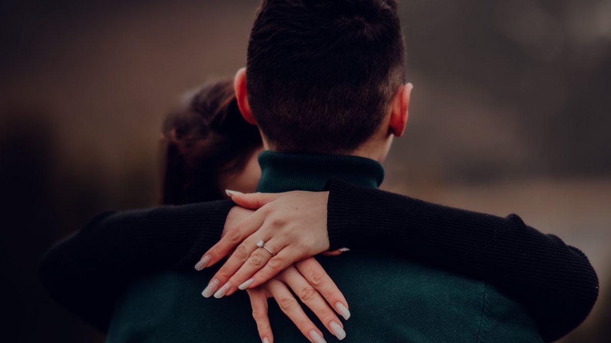 Casal abraçado, as mãos entrelaçadas
